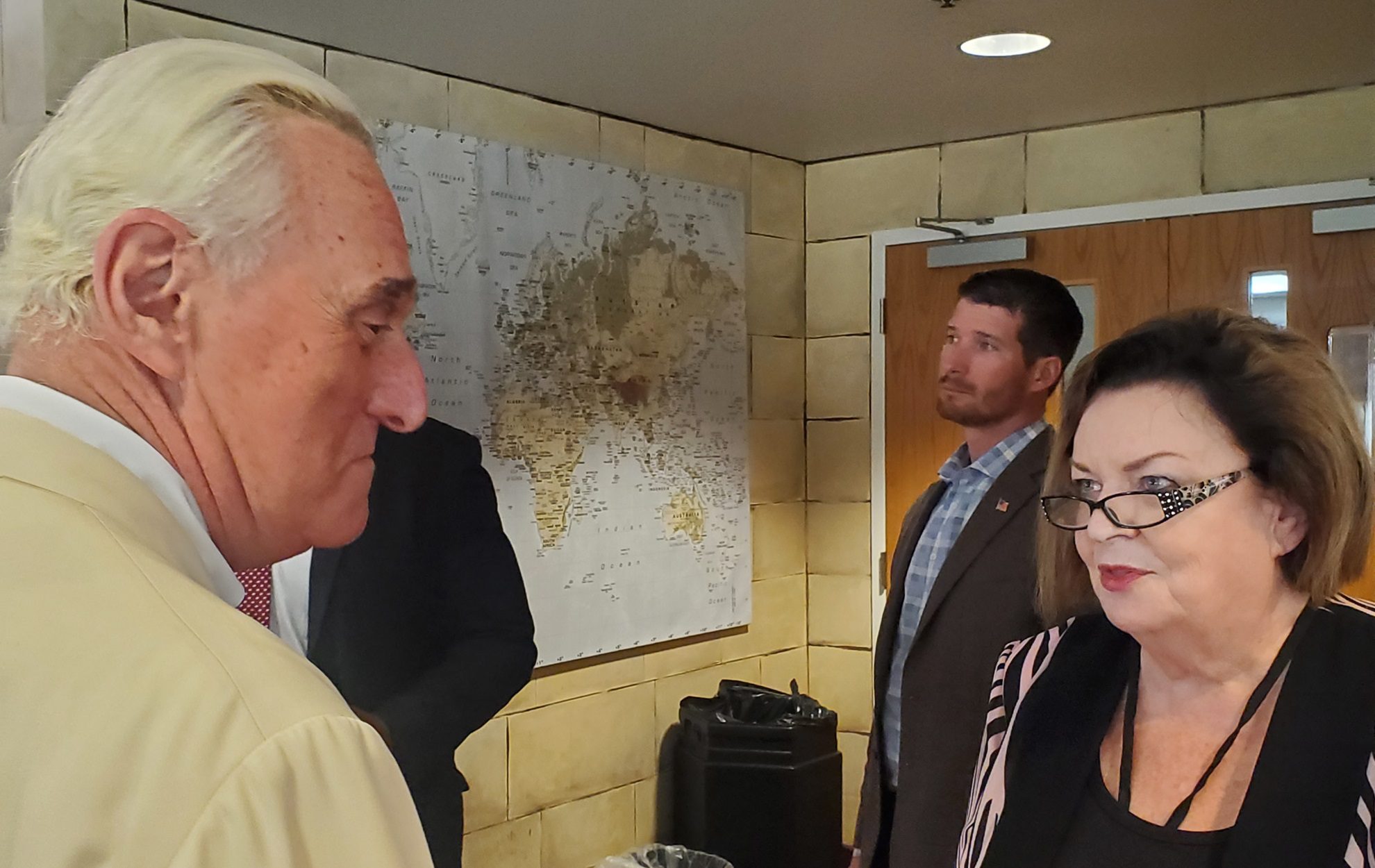 Two men and a woman engaged in conversation indoors.